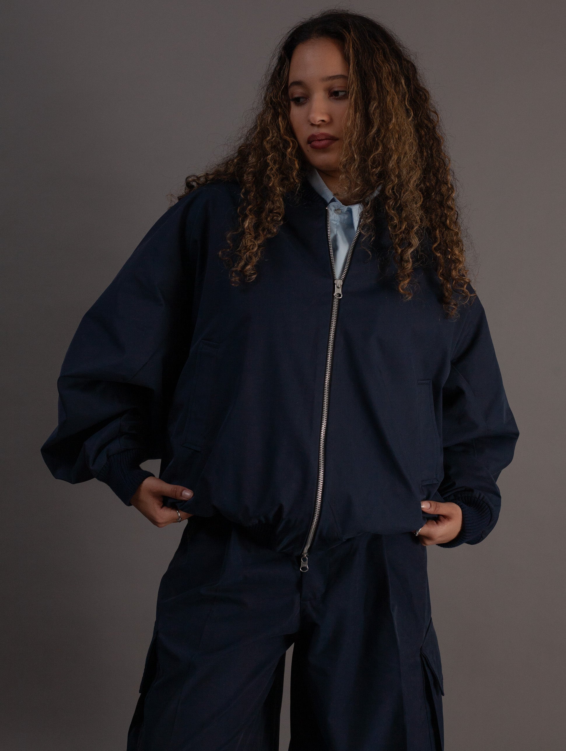 Person wearing a navy blue jacket and pants on a gray background