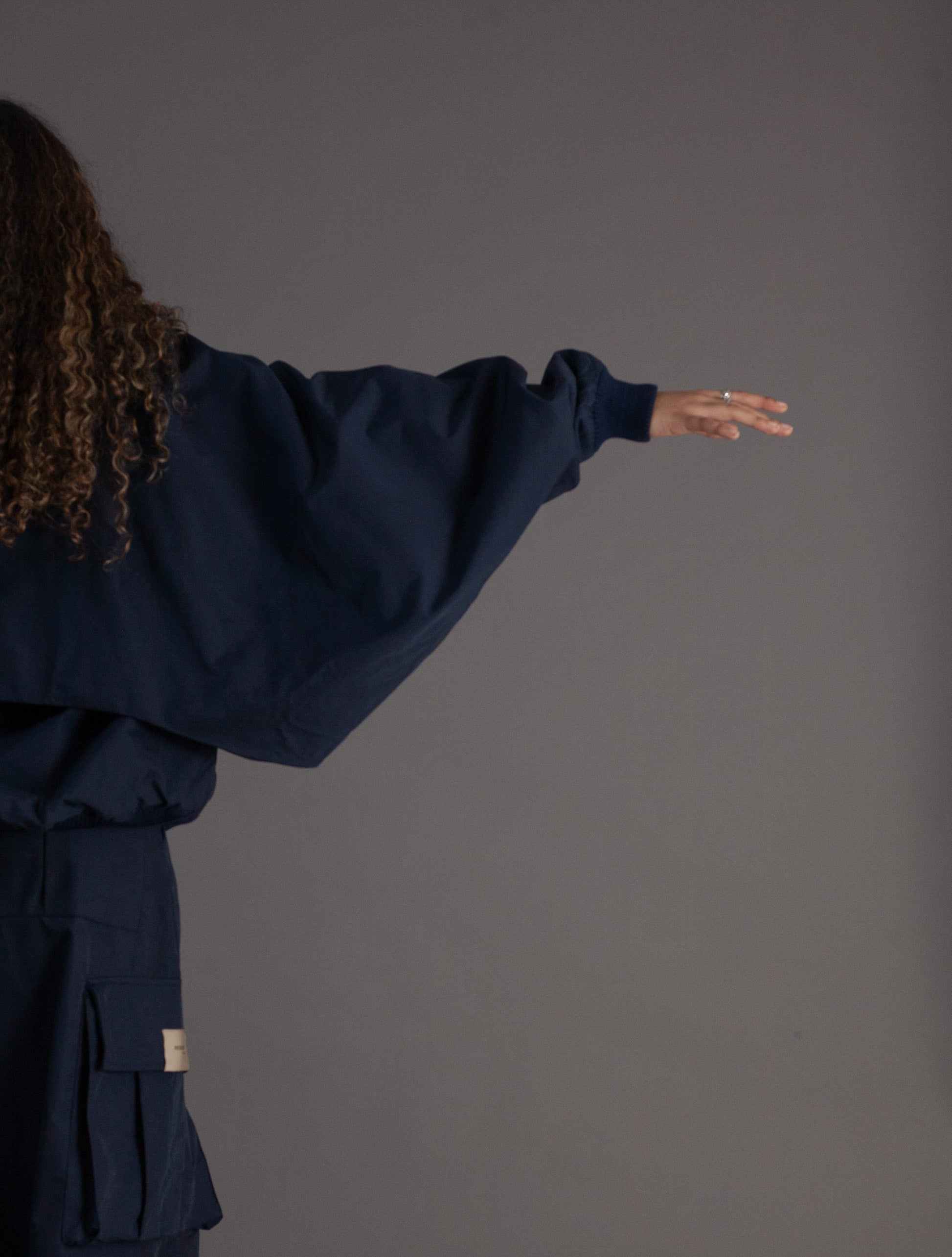 Person wearing a navy blue oversized jacket against a gray background