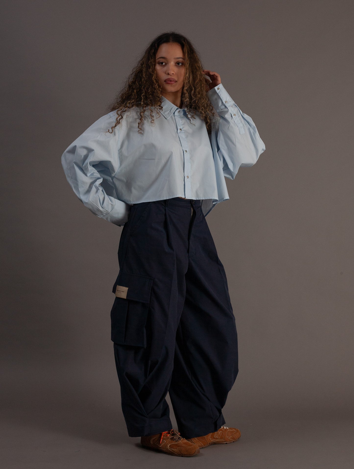 Person wearing a light blue shirt and dark blue cargo pants on a gray background