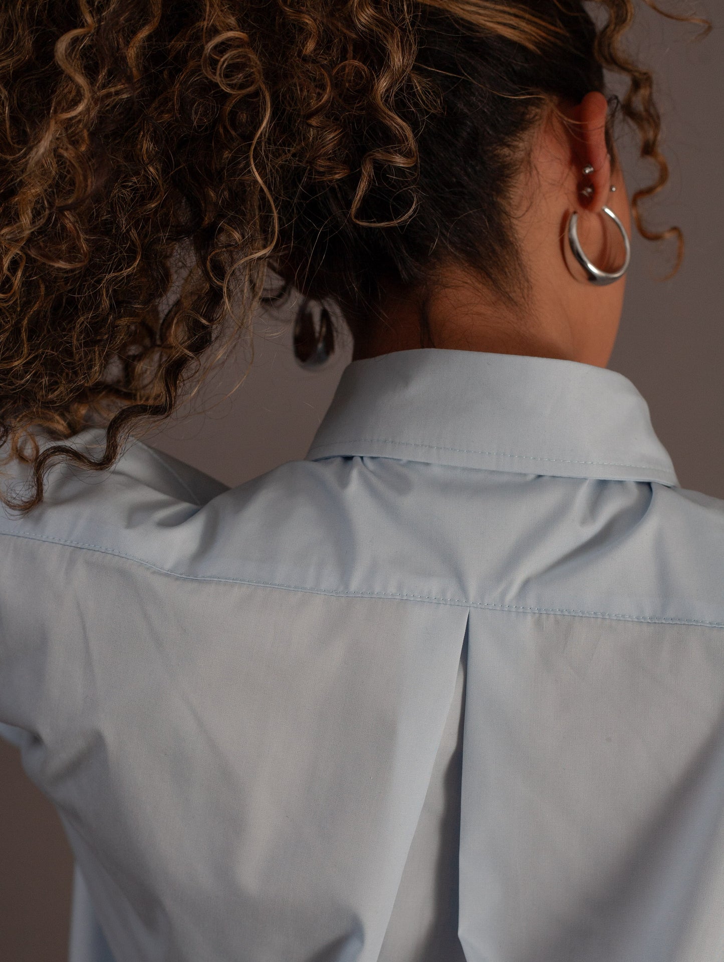 Person wearing a light blue shirt with a neutral background