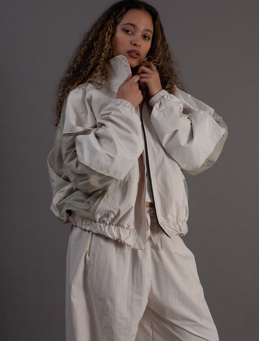 Woman wearing a light-colored outfit against a gray background
