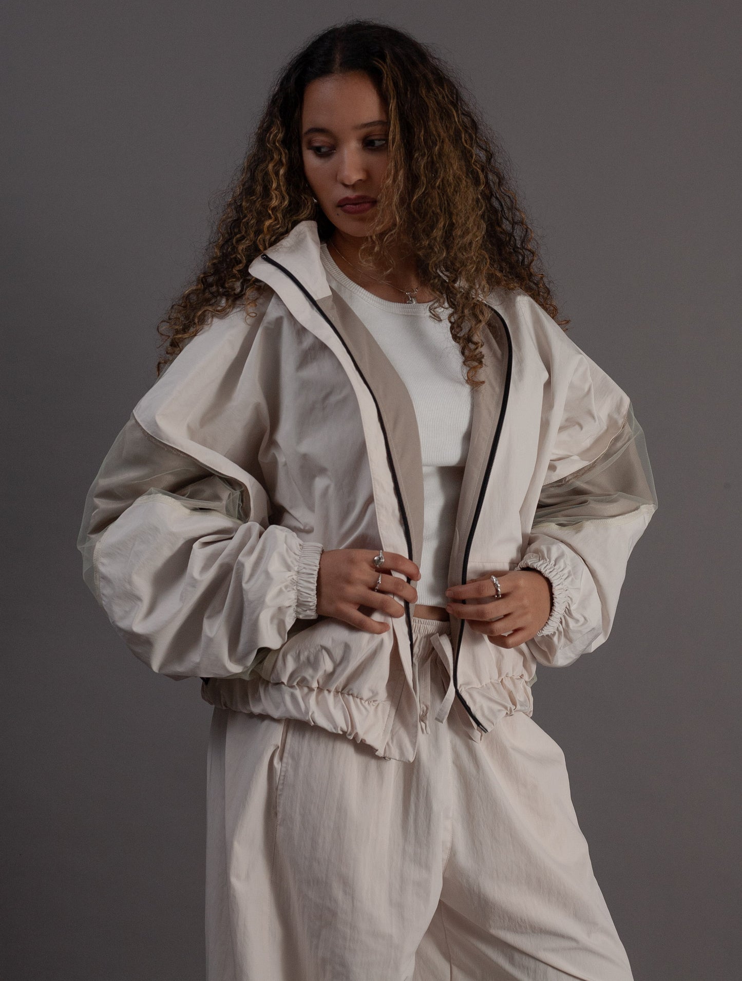 Woman wearing a beige tracksuit against a gray background