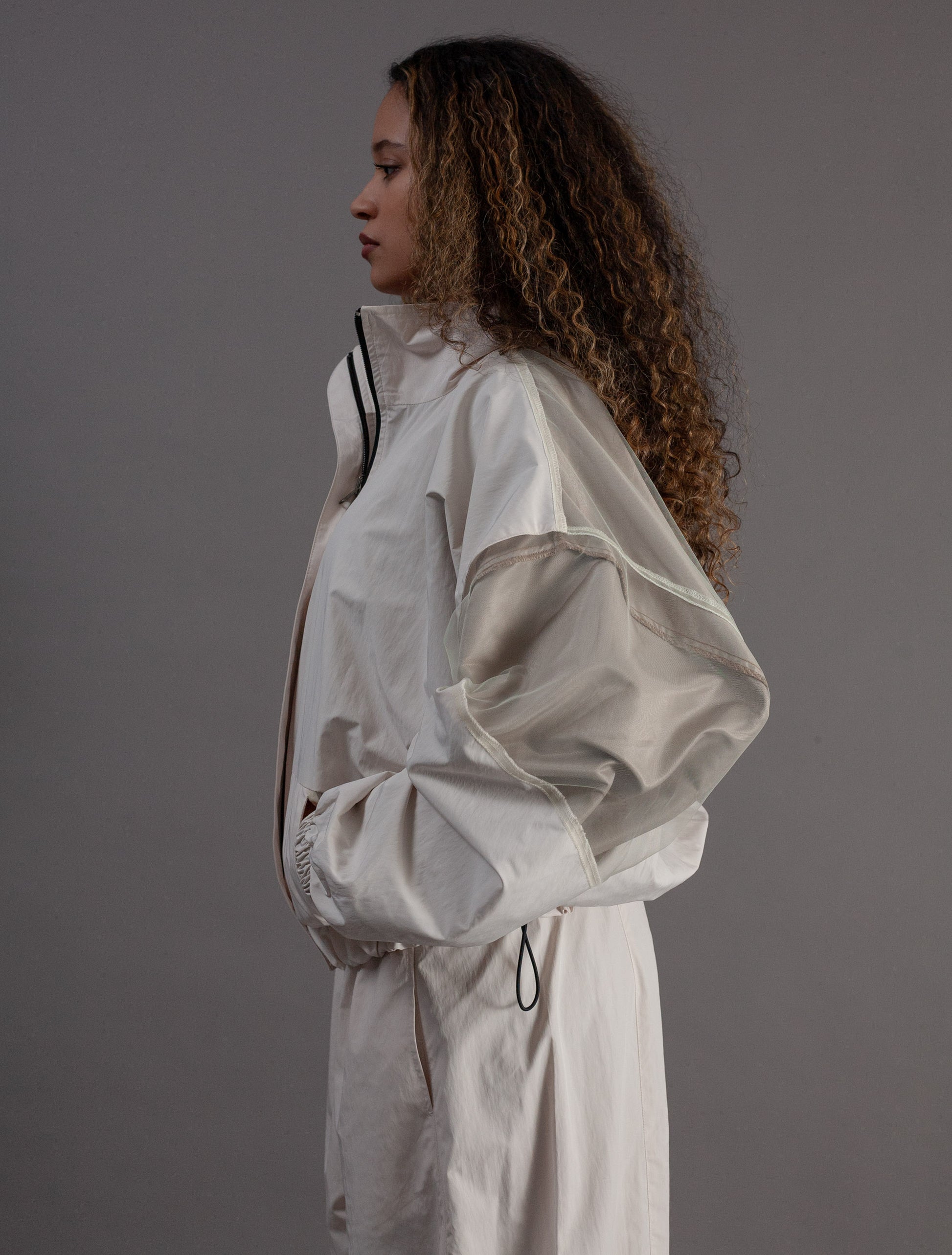 Person wearing a light gray tracksuit against a plain background