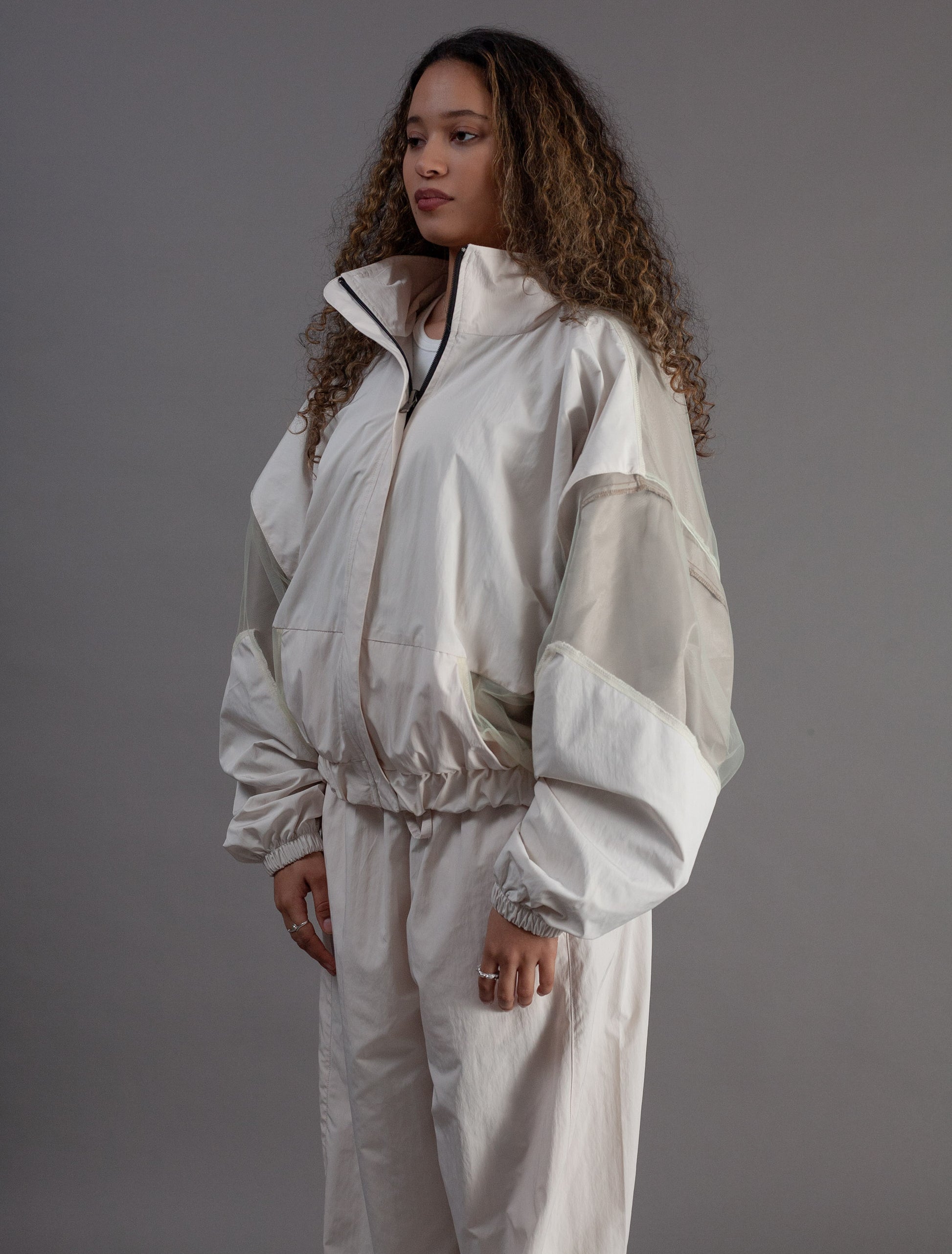 Person wearing a white tracksuit against a gray background