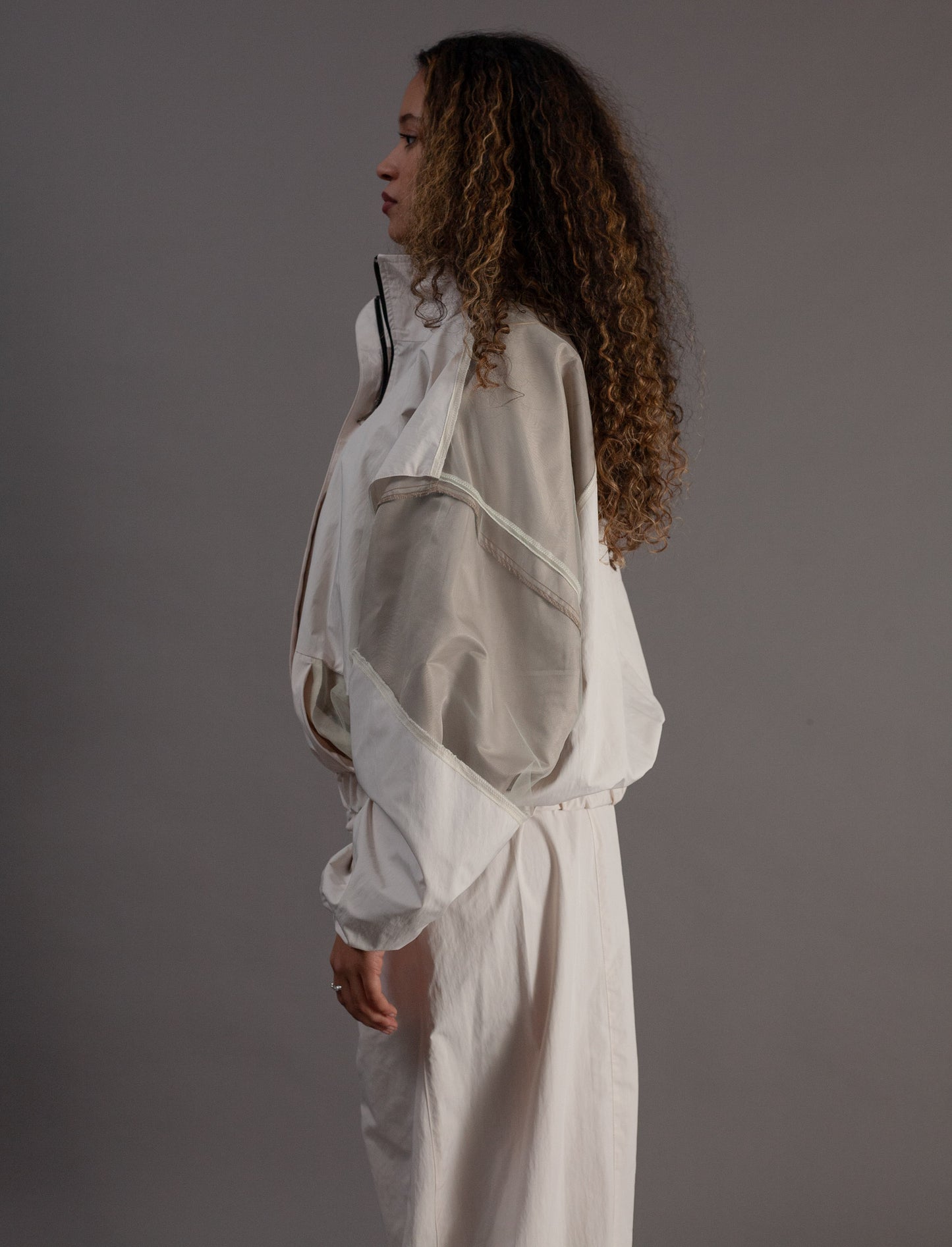 Person wearing a sheer white outfit against a gray background