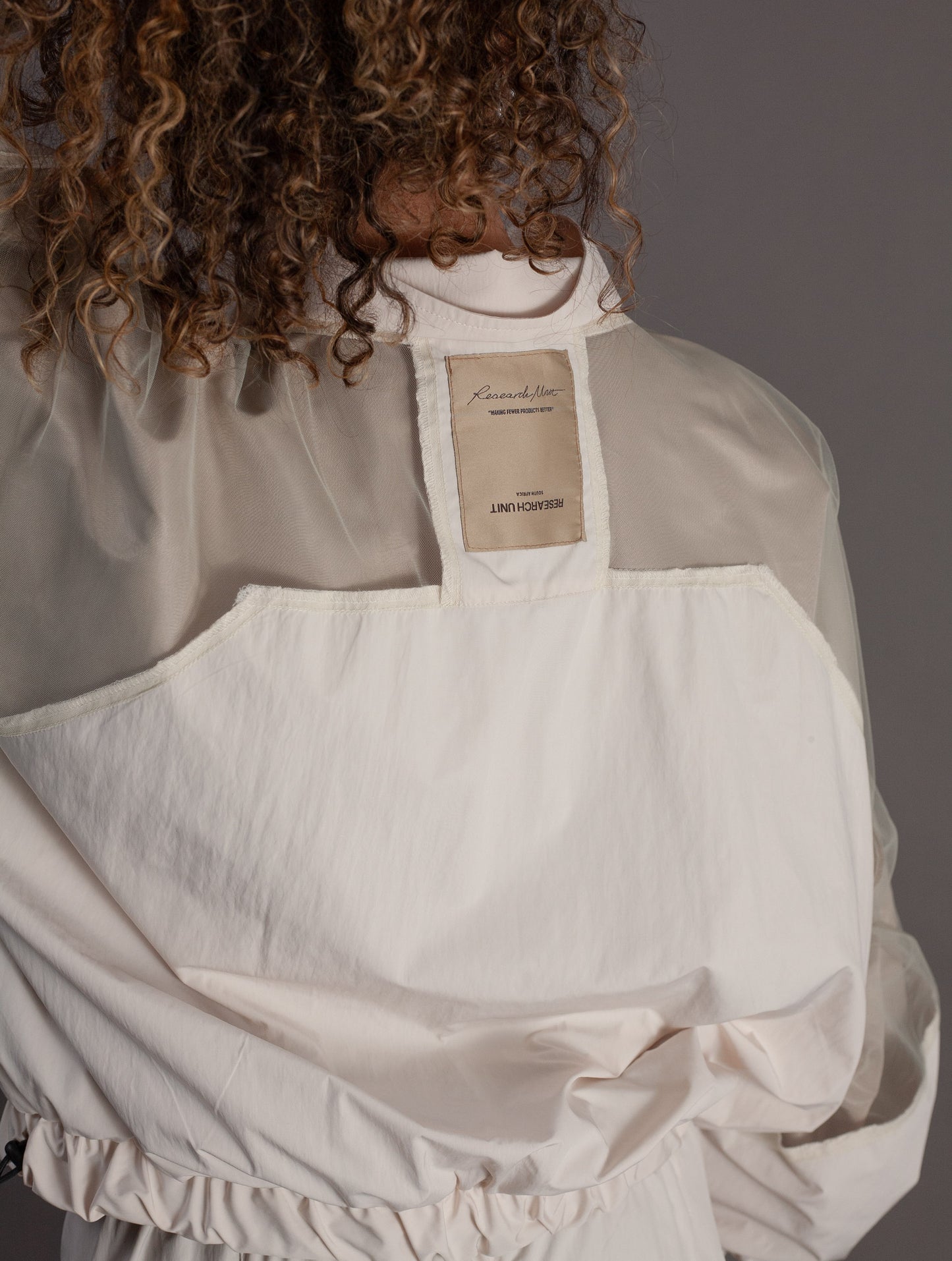 Person wearing a beige apron with a brand label on a gray background