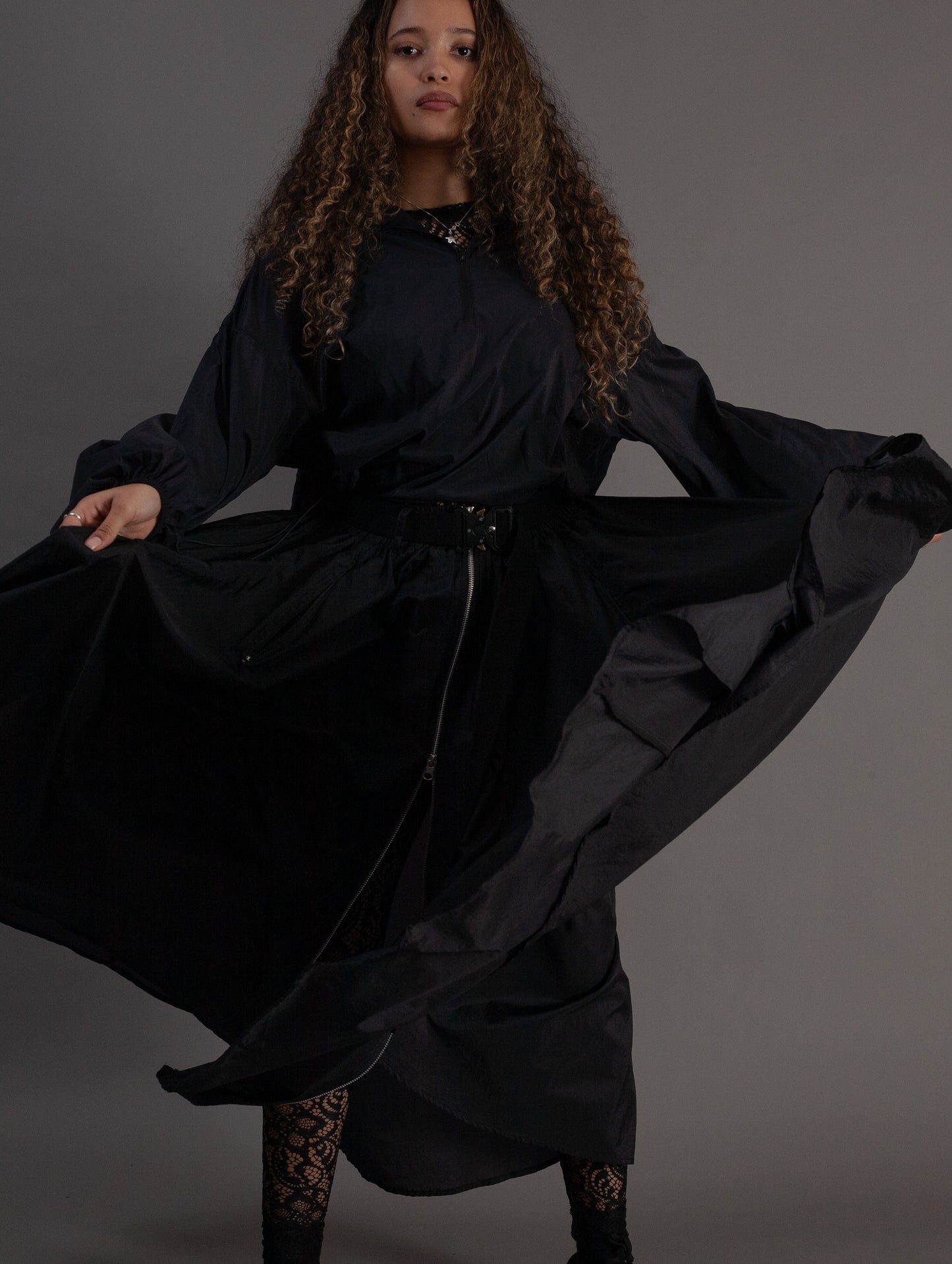 Person wearing a flowing black skirt against a gray background