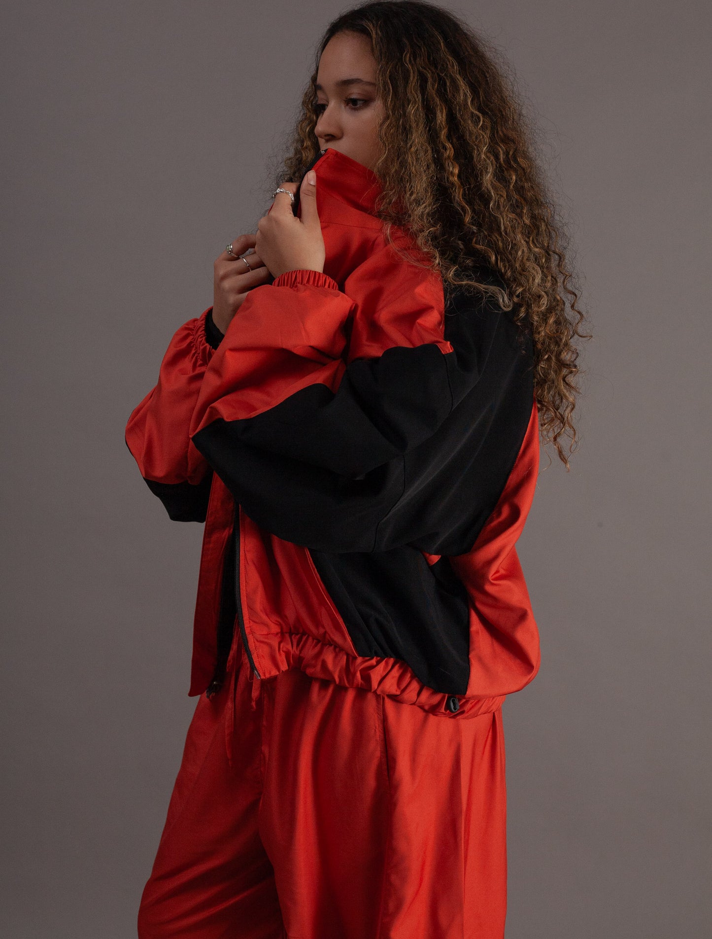 Person wearing a orange and black jacket against a gray background