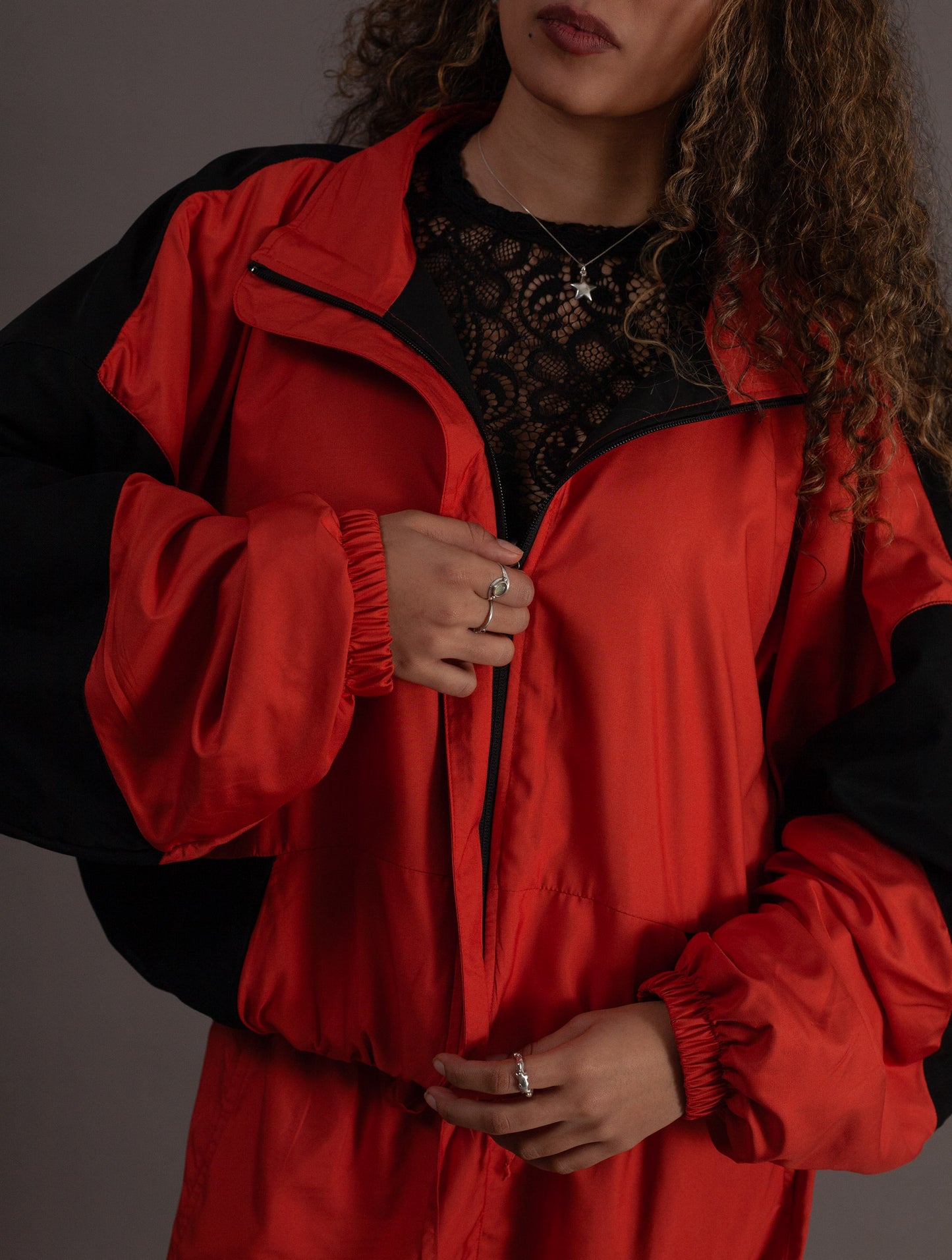 Person wearing a orange and black jacket against a gray background