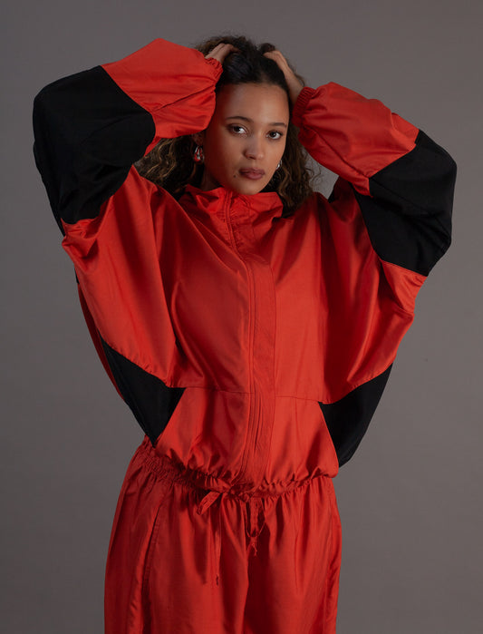 Person wearing a orange and black jacket against a gray background