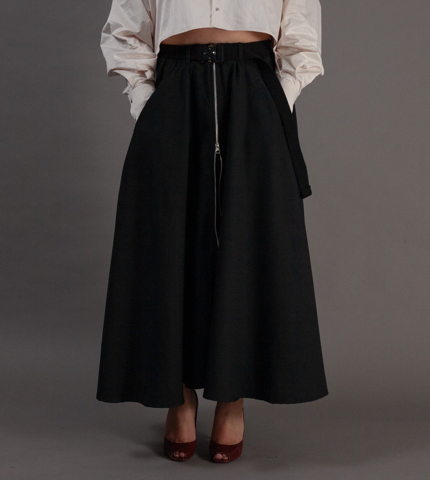 Woman wearing a white blouse and black skirt against a gray background