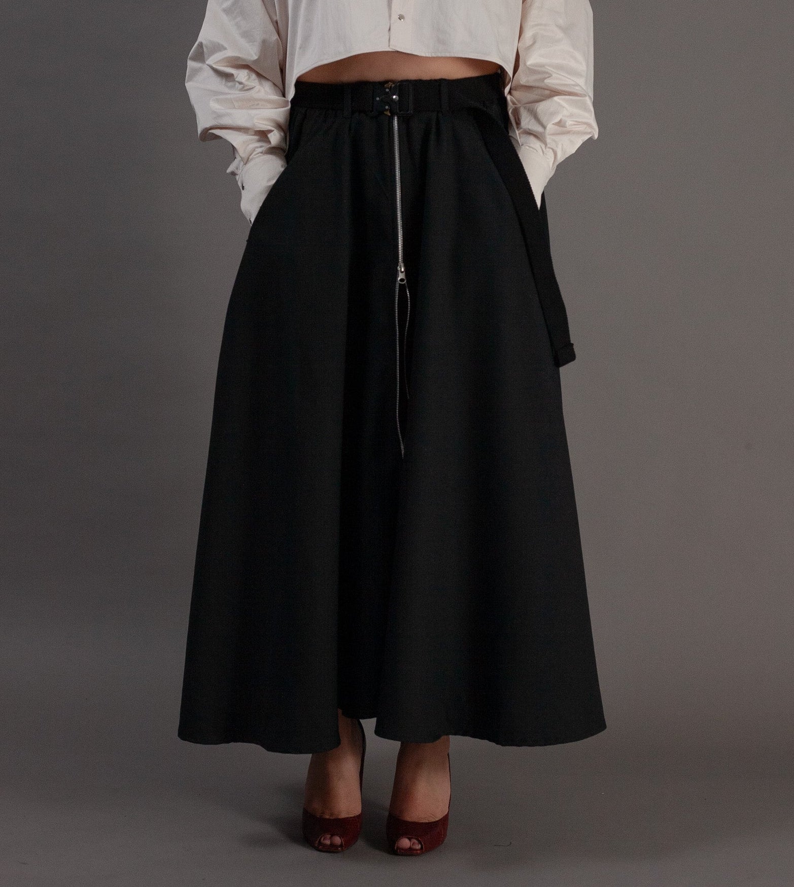 Woman wearing a white blouse and black skirt against a gray background