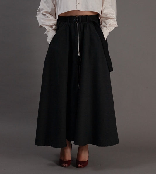 Woman wearing a white blouse and black skirt against a gray background