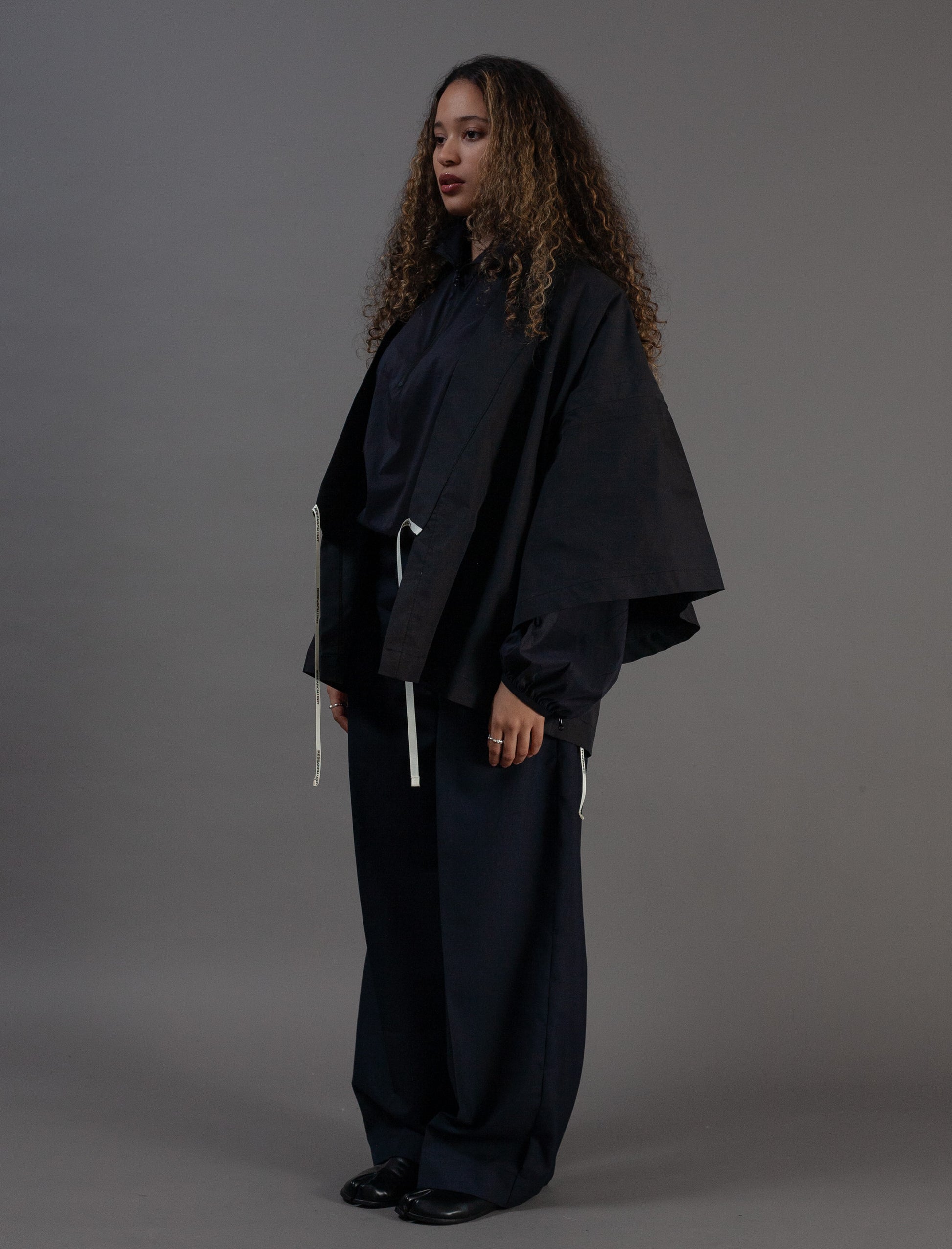 Person wearing a black kimono against a grey background