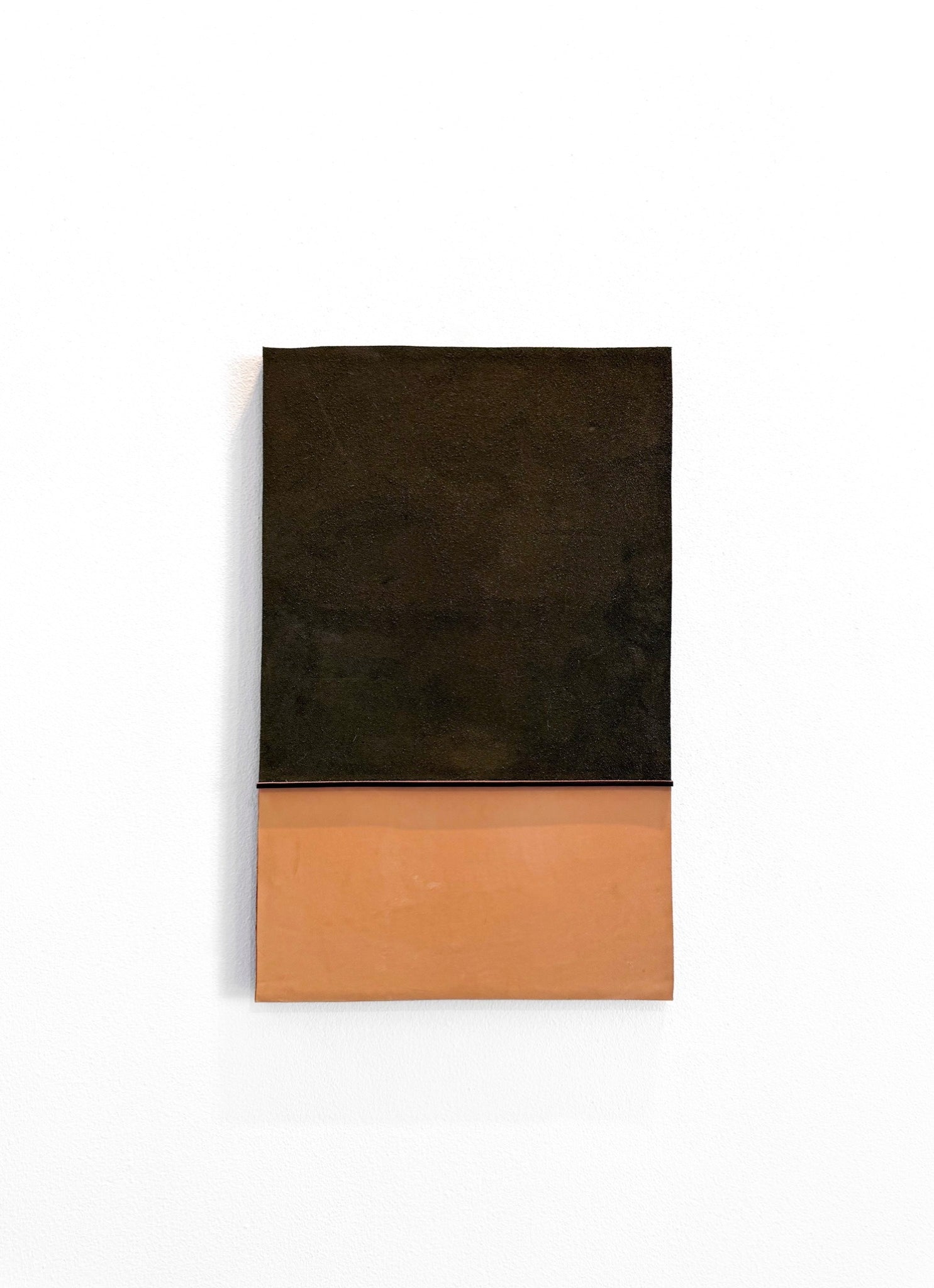 A minimalist abstract wall art piece featuring a split design with a dark, textured black upper half and a smooth terracotta orange lower half, mounted on a clean white wall.
