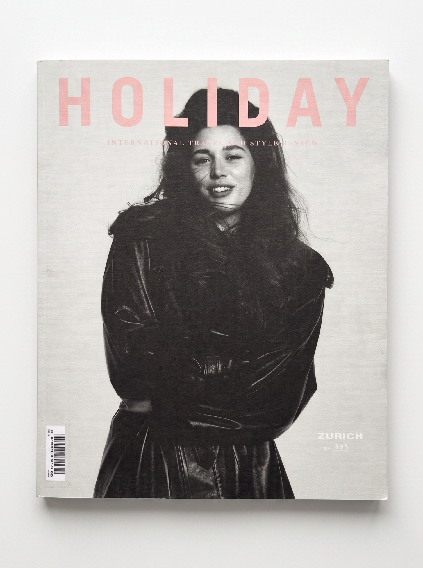A magazine titled 'HOLIDAY' with a black-and-white portrait cover of a woman in a dark coat, photographed against a light gray background.