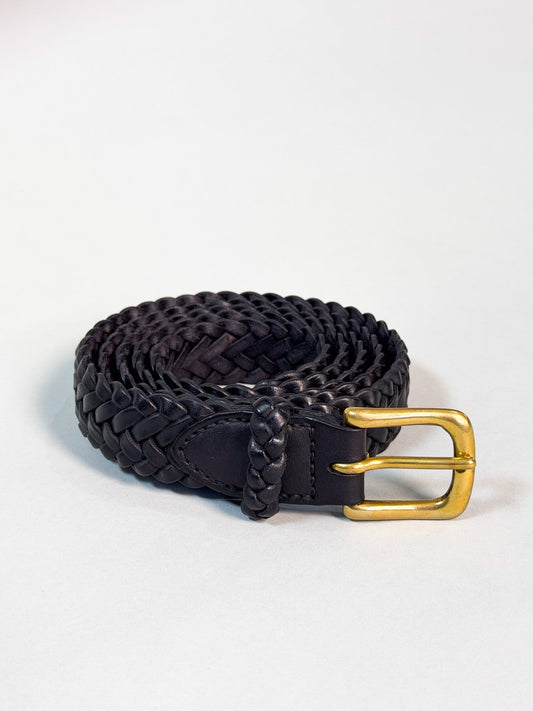 A black braided leather belt with a polished gold-tone buckle, coiled on a light gray background.