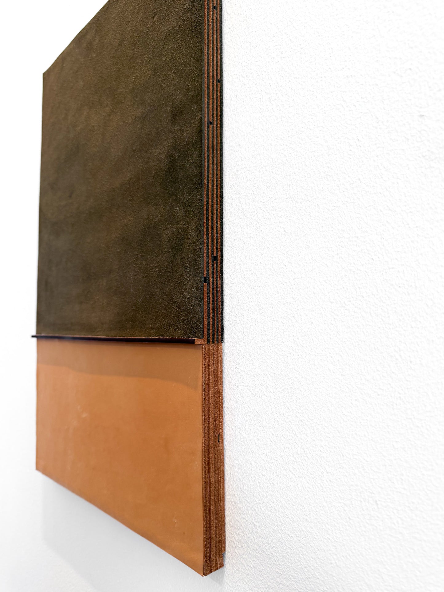 A minimalist wall-mounted art piece featuring a two-tone design with a dark brown textured top section and a warm terracotta orange bottom section, shown against a white wall.