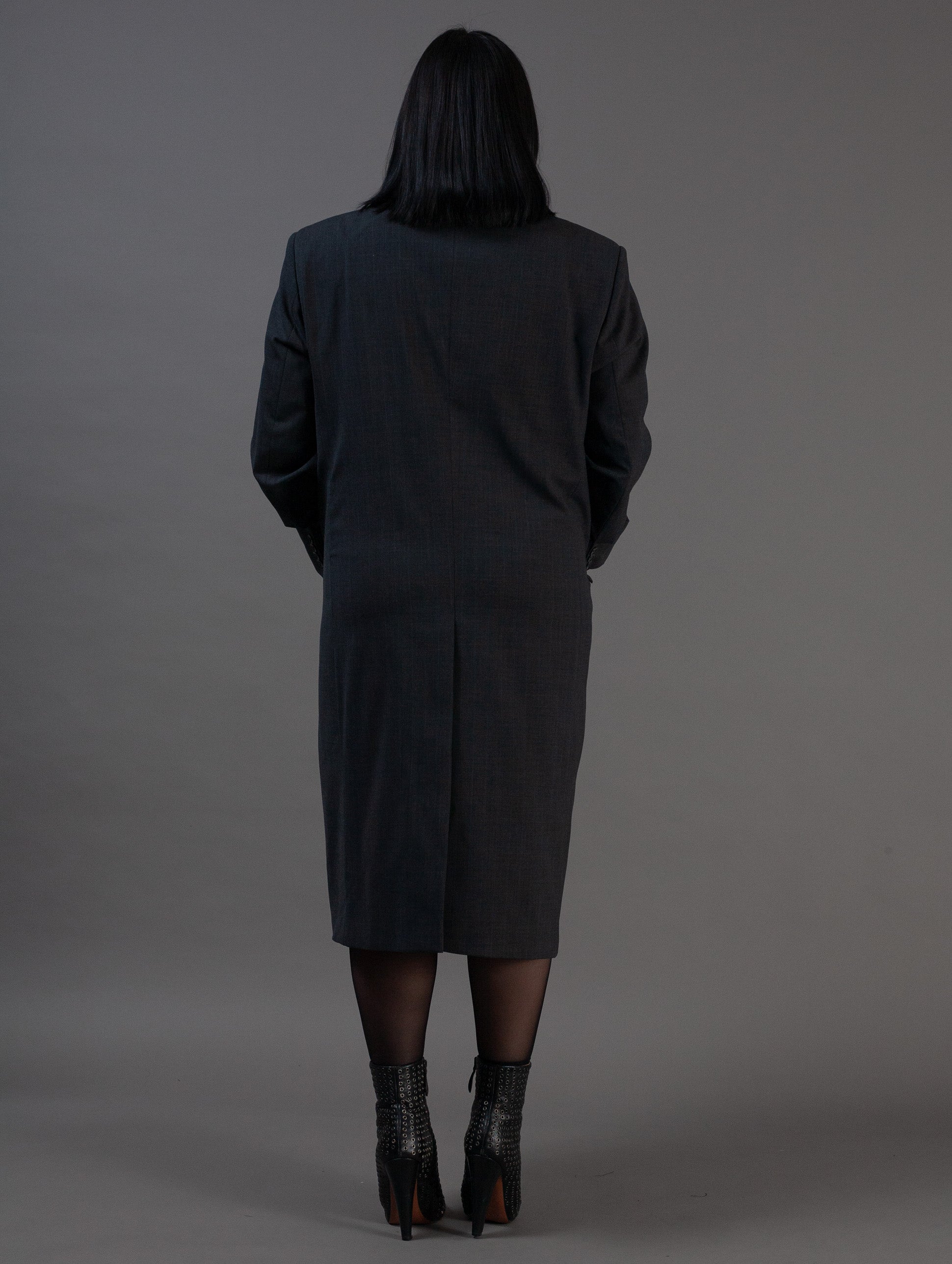 Person wearing a dark gray coat against a plain background