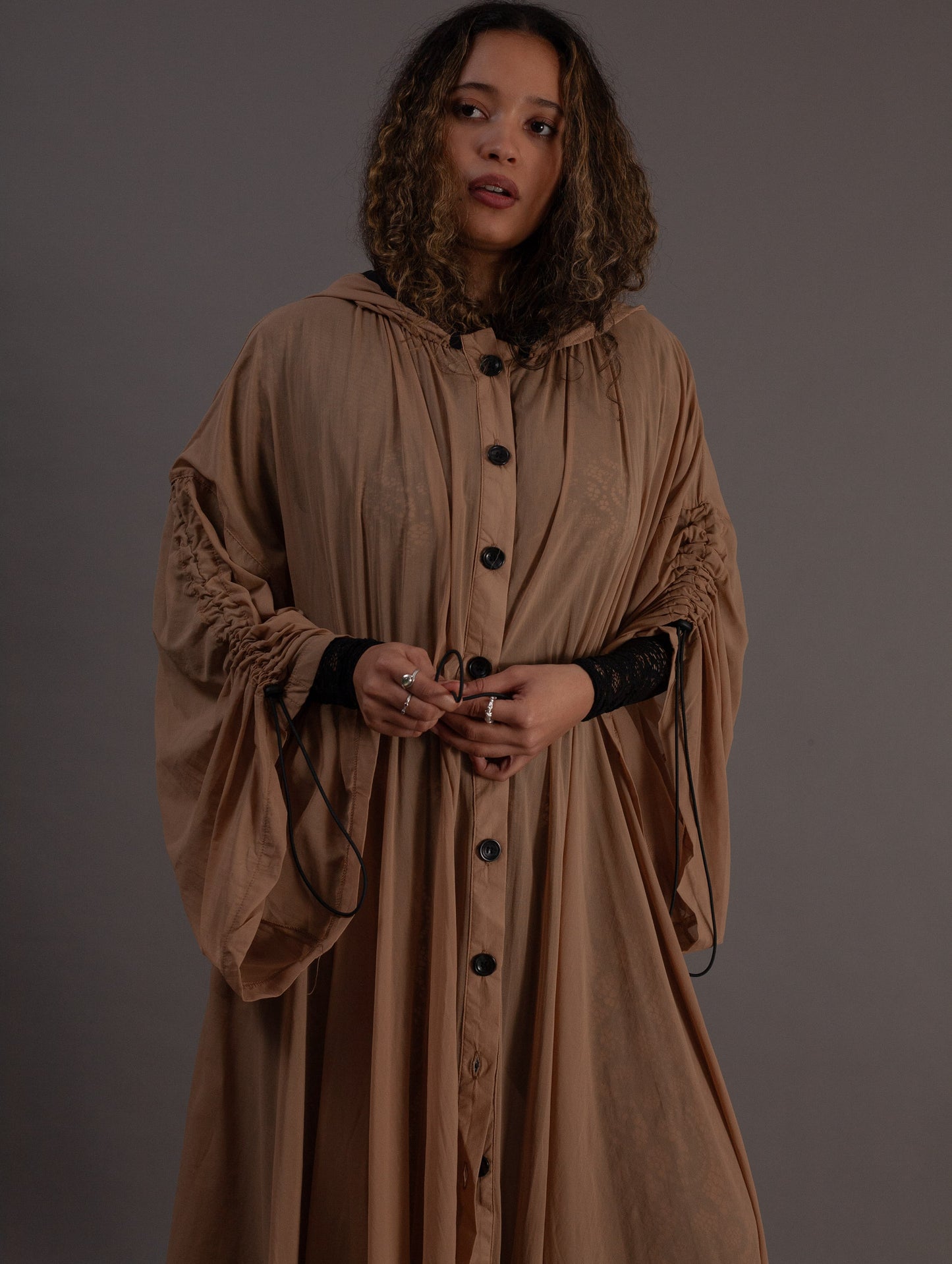 Woman wearing a long beige Osaka dress with black buttons 
