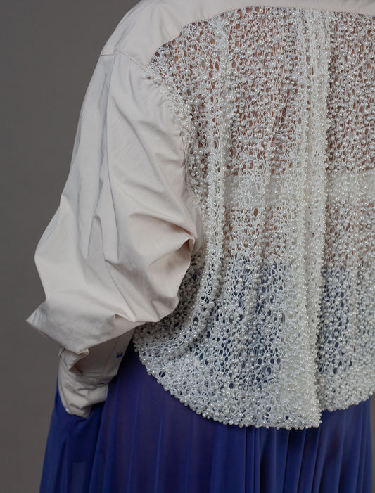 Close-up of a garment with pearls at the back of a plain shirt