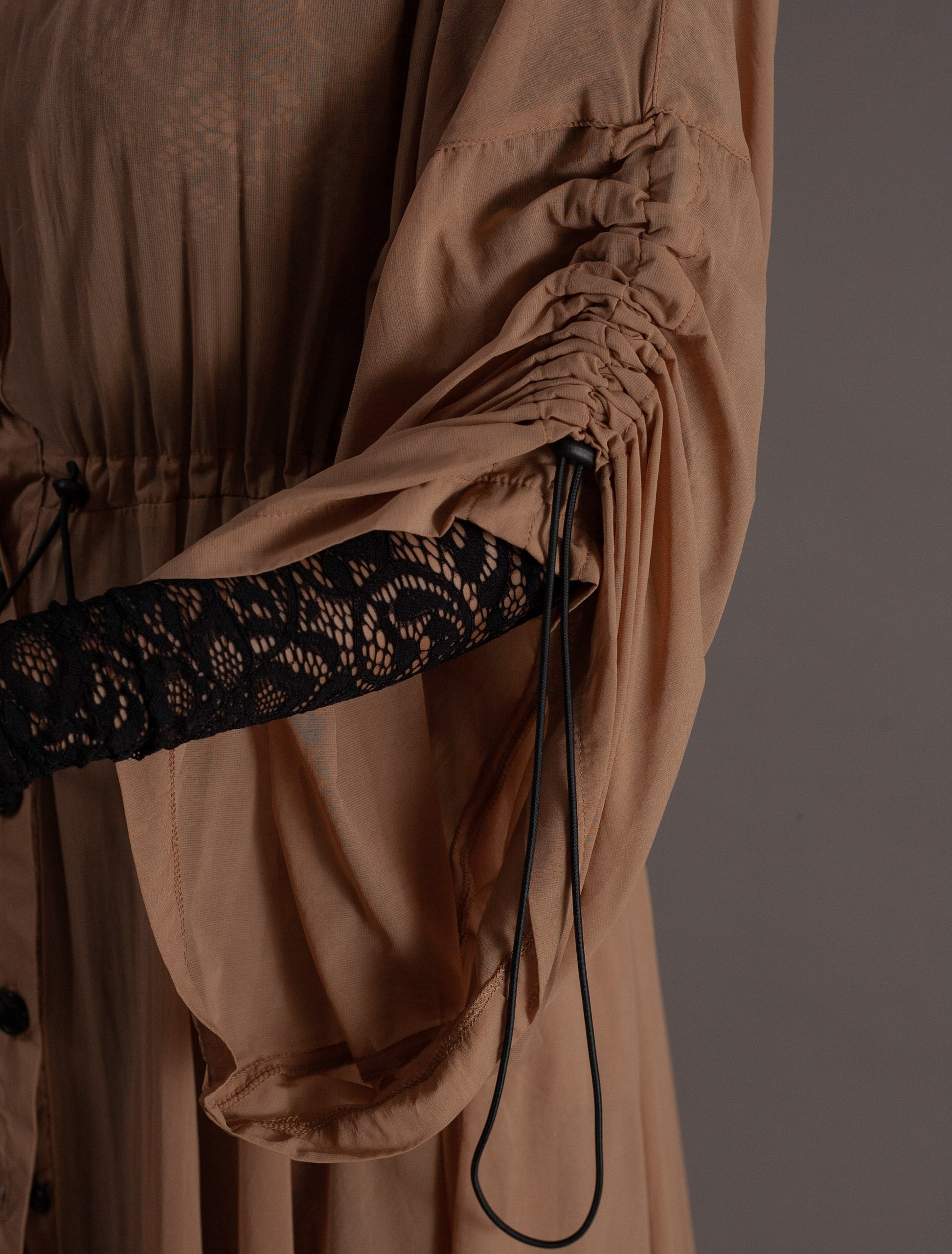 Close-up of a beige garment with a black lace top underneath