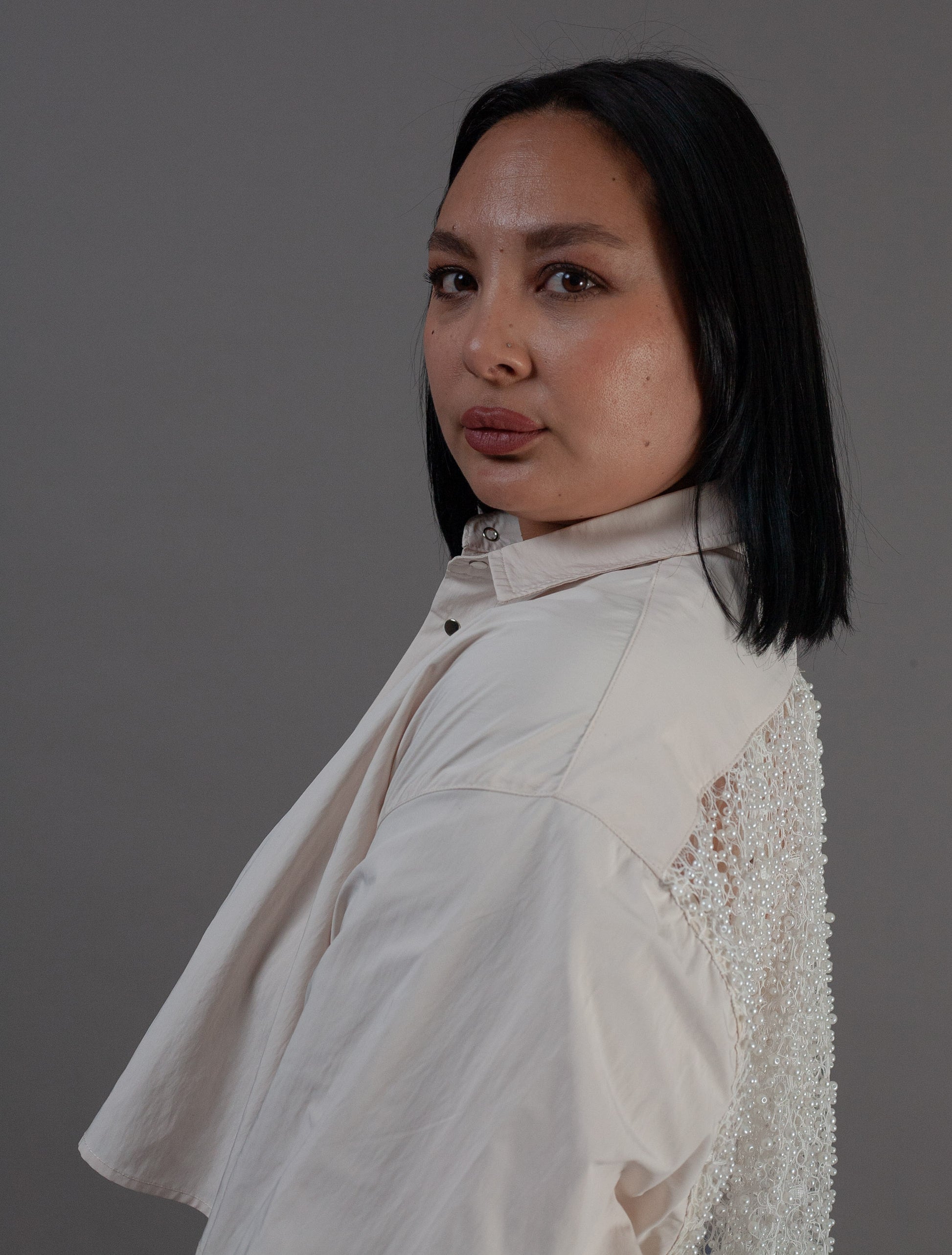 Woman wearing a light-colored outfit with pearl details 