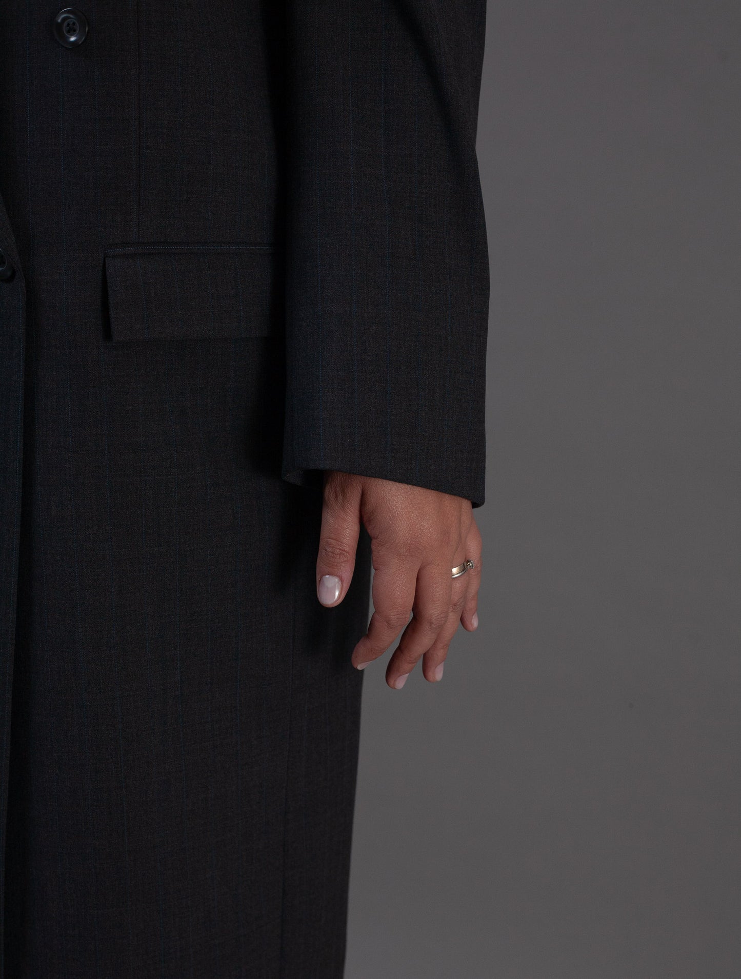 Person wearing a black coat with a plain gray background