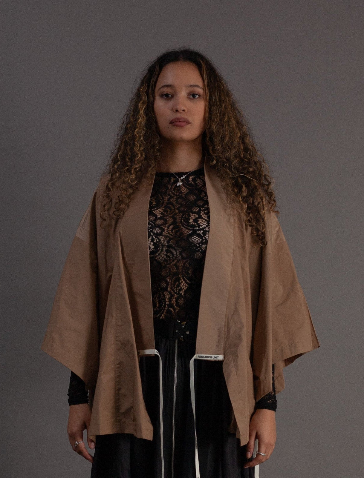 Woman wearing a beige kimono over a black skirt with a lace top 