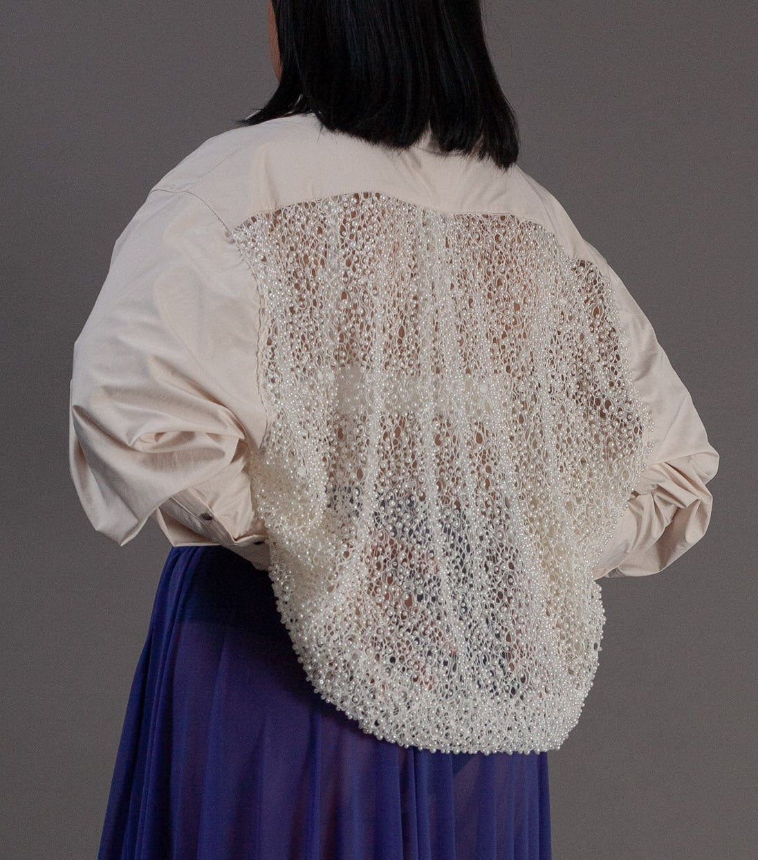 Person wearing a white blouse with pearl details 