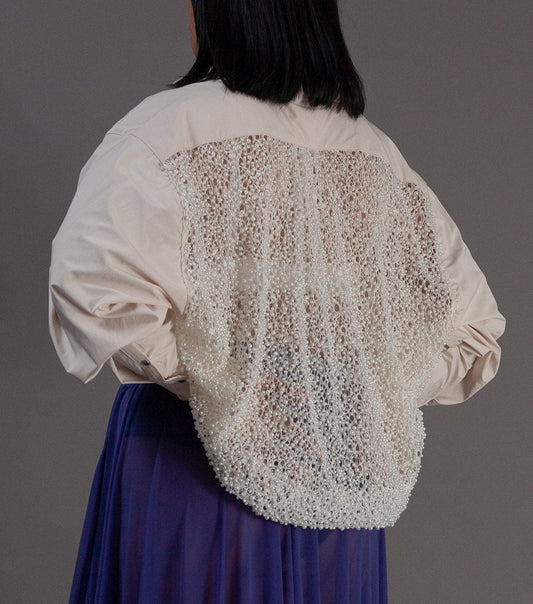 Person wearing a white blouse with pearl details 
