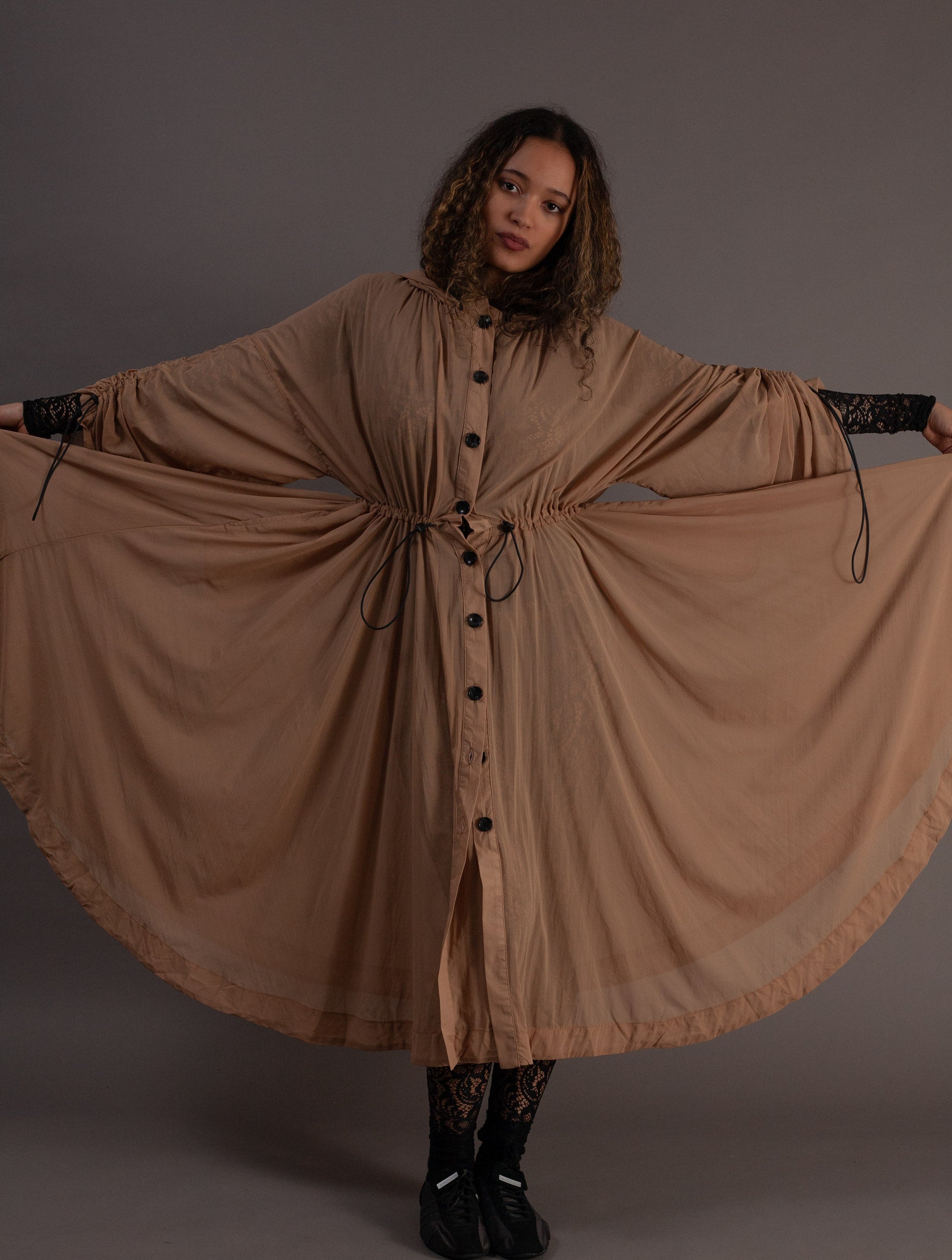 Woman wearing a long beige dress with black buttons 
