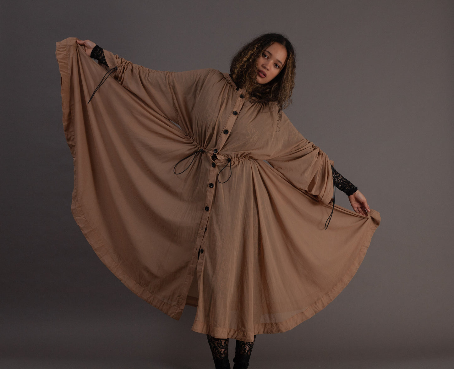 Woman wearing a long beige dress with black buttons 