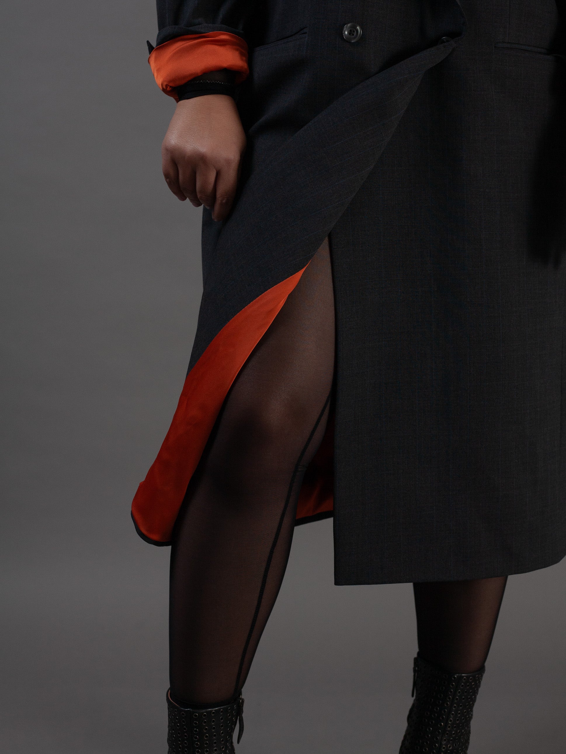 Person wearing a grey pinstripe coat with orange lining