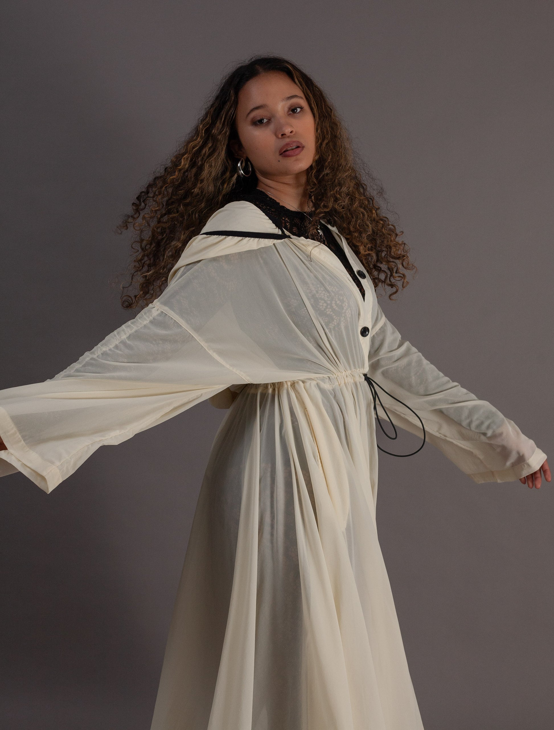 Person wearing a long, light-colored coat with black buttons 
