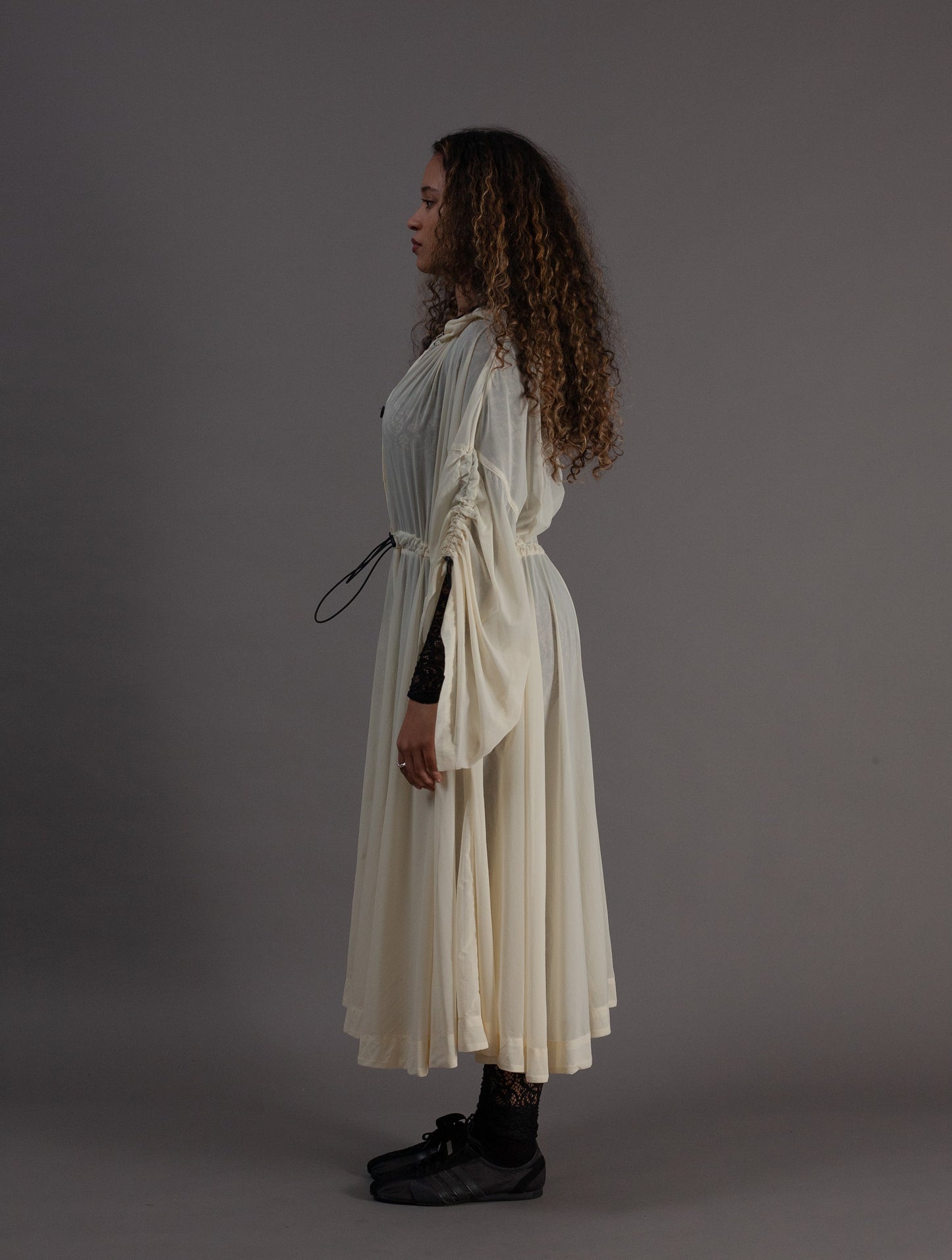 Person wearing a long, light-colored coat with black buttons 